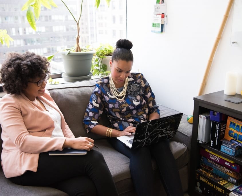 Two ladies sitting on coach with laptop christina-wocintechchat-com-dKBTFoarrOU-unsplash two women on couch with laptop performance conversations