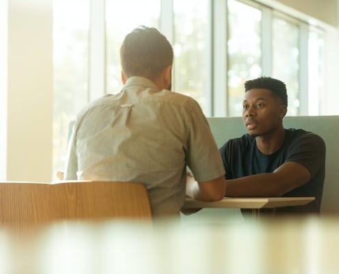 two men sitting in booth mental health